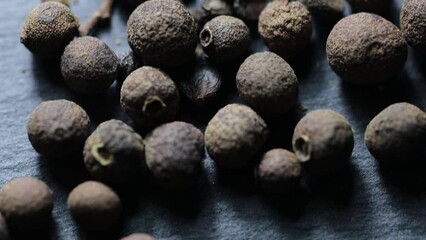 Poster - natural black peppercorns on a stone stand. vertical camera movement