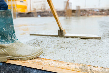 Construction worker, mason is leveling fresh concrete using handmade tool