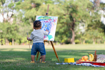 Wall Mural - Back view of kid boy painting on canvas in the garden, Happy child boy drawing a picture outdoors