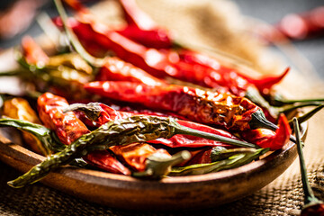 Canvas Print - Pods of dried chili peppers in a wooden plate on a napkin. 