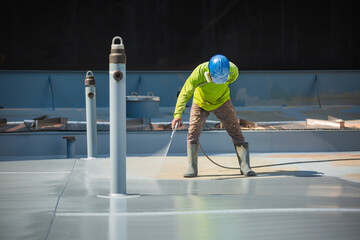 A male worker holding an industrial spray gun used for roof plate tank surface on steel industrial painting and coating.