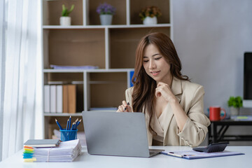 Asian businesswoman working with financial documents and laptop Inside office worker calculating financial indicators smiling and happy with success and results of business success