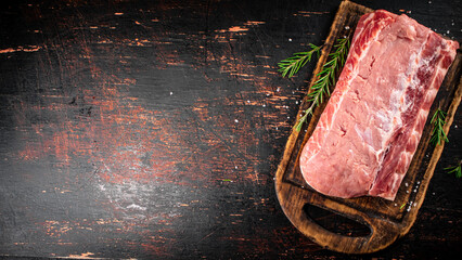 Sticker - A piece of raw pork on a cutting board with a sprig of rosemary. 