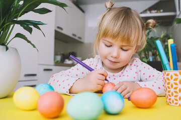 Smiling little girl with colorful eggs preparing for Easter Holiday. Kids painting easter eggs. Creative background for preschool and kindergarten. Family traditions and symbols of celebration.