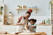 © Seventyfour - Happy black mother and daughter playing with dough baking together