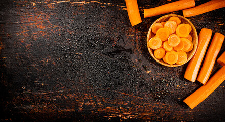 Poster - Round pieces of fresh carrots on a wooden plate. 