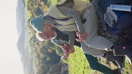 Wall Mural - Senior couple having break, looking into phone during hiking in autumn nature.