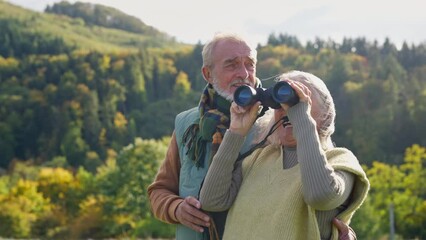 Wall Mural - Senior couple looking at view trough binoculars on autumn walk.