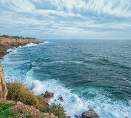 Wall Mural - beautiful cloudy sky and foaming waves approaching rocky shore of the atlantic ocean. beautiful natu