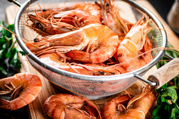 Poster - Boiled shrimp in a colander on a cutting board with parsley. 