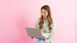 © Pichsakul - Young women working and typing to chatting with colleague on laptop isolated on pink background