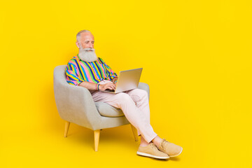 Sticker - Full size portrait of positive smart aged man sit armchair use wireless netbook isolated on yellow color background