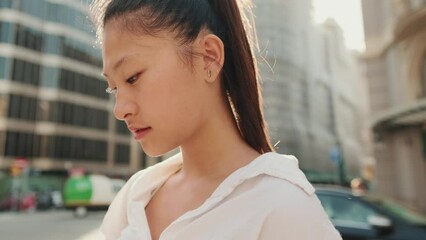 Wall Mural - Close up, young woman standing outdoors looking up and using the map app on her smartphone. Backlight