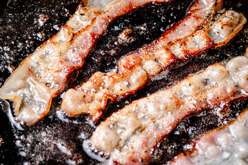 Poster - Pieces of bacon are fried in boiling oil with air bubbles. 