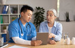 © Prostock-studio - Serious middle aged korean male doctor showing tablet and consulting senior european lady patient in clinic