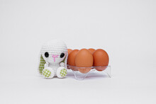 A Knitted Rabbit And Real Easter Eggs On A White Table. Photo . Background With Copy Space