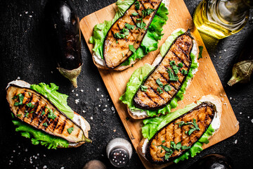 Sticker - Sandwich with grilled eggplant and lettuce on a wooden cutting board. 