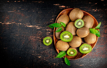 Poster - Fresh kiwi with leaves on a wooden plate. 