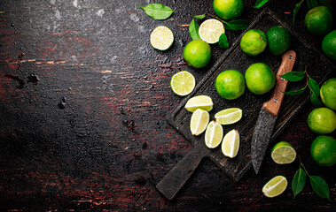 Canvas Print - Sliced lime with leaves on a cutting board with a knife.