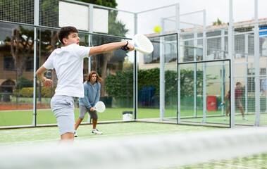 Wall Mural - Portrait of emotional guy enjoying friendly padel tennis match at outdoors court