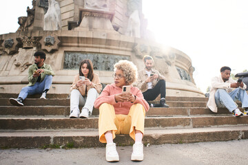 Group of people using phone with serious face. Friends focused on their mobiles siting on a bench outdoors in a park. Technology addicts concept. High quality photo