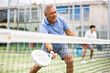 © JackF - Portrait of elderly man playing paddle tennis with friends on open court. Active lifestyle concept