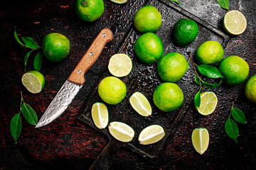 Canvas Print - Sliced lime with leaves on a cutting board with a knife.