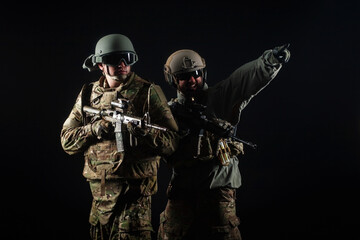 Wall Mural - two soldiers in military uniform with weapons in a special operation at night, special forces attack against a dark background, elite troops