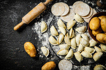 Canvas Print - Raw potato dumplings on a stone tray with rolling pin and flour. 