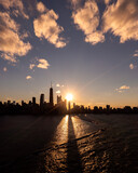 Fototapeta Tęcza - Beautiful downtown Chicago skyline aerial drone photograph above Lake Michigan during the  autumn equinox sunset as the sun casts a glistening yellow glow and long building shadows over the water.