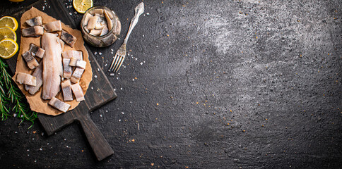 Sticker - Fillet of salted herring on paper on a cutting board. 