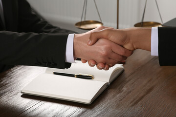 Wall Mural - Law and justice. Notary with client shaking hands at wooden table, closeup