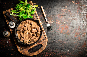 Poster - Liver in a frying pan on a cutting board with parsley and spices. 