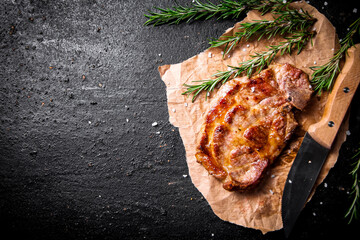 Grilled pork steak on paper with rosemary. 