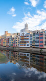 Fototapeta Londyn - Colorful houses reflected in the Onyar river, in Girona, Catalonia, Spain. Church of Sant Feliu and Cathedral of Santa María in the background