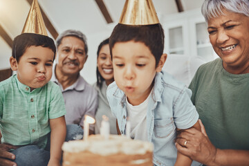 Poster - Kids, birthday cake and kid blowing candles at a house at a party with food and celebration. Children, celebrate event and family together in a kitchen with a smile and happiness with parent love