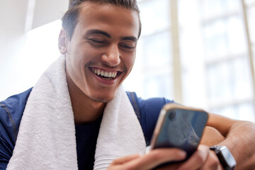 Poster - Man relax, fitness and smartphone in gym, smile and rest after workout, training and typing for social media. Male, athlete and guy with cellphone, break and connection for chatting and with towel