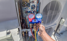 Air Conditioning, HVAC Service Technician Using Gauges To Check Refrigerant And Add Refrigerant.