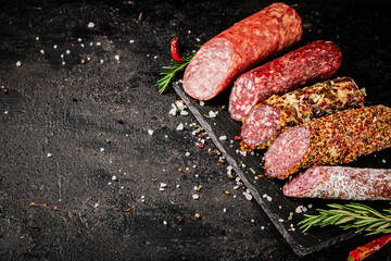 Wall Mural - An assortment of delicious salami sausage on a stone board with rosemary. 