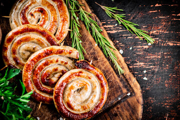 Wall Mural - Grilled sausages on a cutting board with parsley and rosemary. 