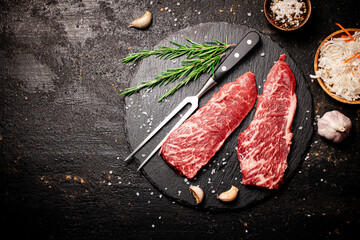 Raw steak on a stone board. On a black background.