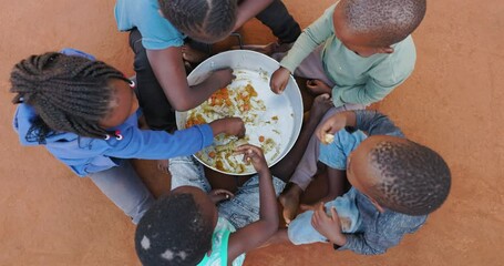 poverty in africa. hungry black african children scraping remains of food from the bottom of a commu