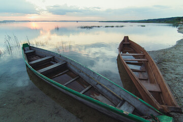 Close up wooden boats on sand shore concept photo. Peaceful lake in evening. Front view photography with blurred background. High quality picture for wallpaper, travel blog, magazine, article