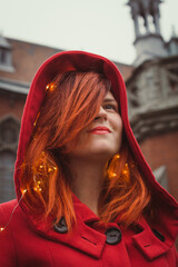 Wall Mural - Close up confident lady in red coat on city street portrait picture. Closeup front view photography with vintage building on background. High quality photo for ads, travel blog, magazine, article