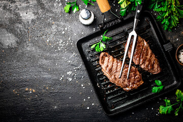 Wall Mural - Grilled steak with parsley in a frying pan. 