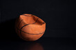 Old deflated basketball black dark background, worn out damaged ball