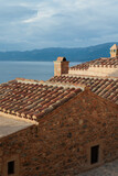Pink red orange masonry houses with tile rooftops over blue sea. Medieval greek village Monemvasia