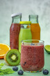 Green, orange, red smoothies in glass bottles and a glass smoothies.