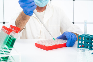 Wall Mural - male laboratory assistant works with automatic pipette filling glass jars