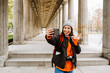 © Drobot Dean - Excited asian woman tourist taking selfie and waving during walk through the old city street